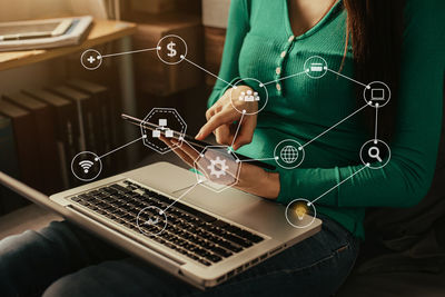 Midsection of woman using mobile phone while sitting on table