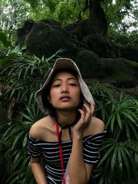 Portrait of beautiful young woman against trees