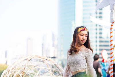 Young woman standing against skyscrapers in city