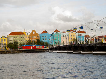 Exterior of houses by sea against sky