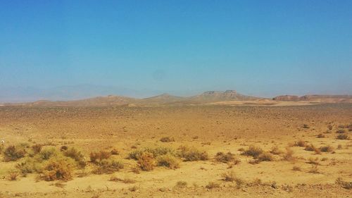 Scenic view of desert against clear blue sky