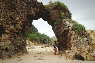 Full length of man with horse on rock at beach