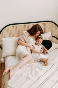 Happy mom and little daughter baby relax unwind and play in a cozy room in a cozy house