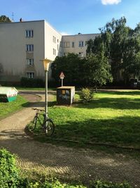 Man on bicycle by house against sky