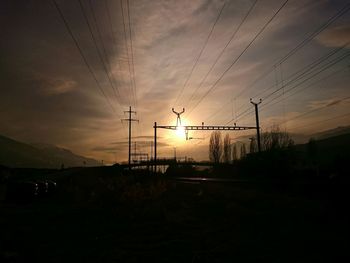 Electricity pylon on landscape against sunset sky