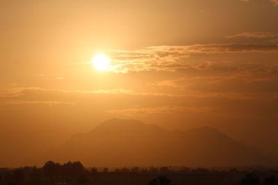 Scenic view of silhouette mountains against orange sky