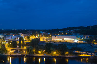 Illuminated city by river against sky at night