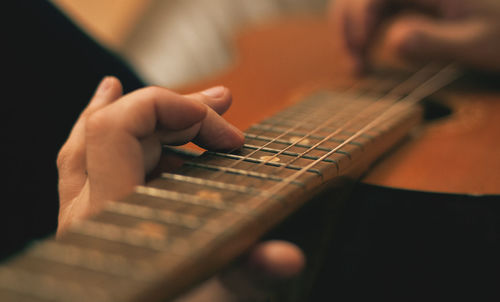 Close-up of hands playing guitar against blurred background