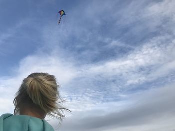 Low angle view of girl flying kite in sky