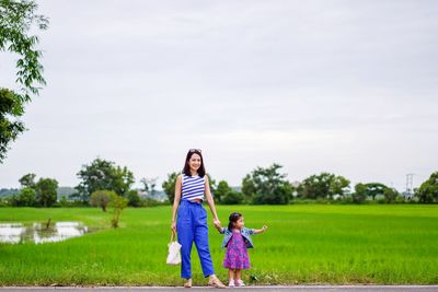 Full length of women on grassy field against sky