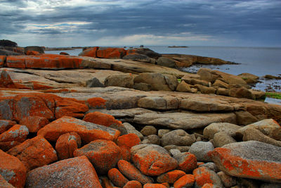 Scenic view of rocky beach against cloudy sky