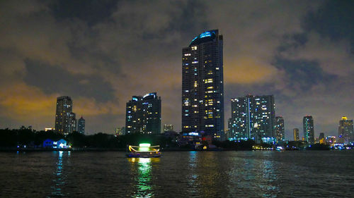 Illuminated buildings in city against sky at night