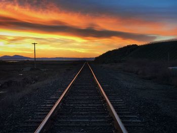 Railroad tracks against sky during sunset