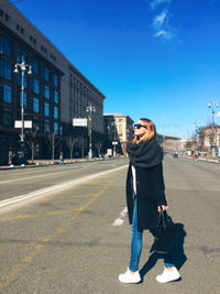 Full length of man standing on road in city against sky