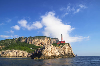 Lighthouse in front of sea against sky