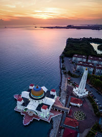 High angle view of buildings by sea against sky during sunset