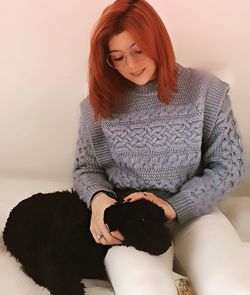 Young woman holding dog while sitting against wall