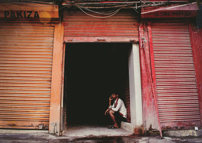 Side view of woman standing against closed door of building