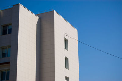 Modern building with electric wire against a blue sky.