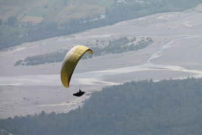 Person paragliding over mountain against sky