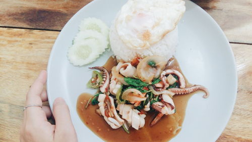 Cropped image of hand holding octopus in plate