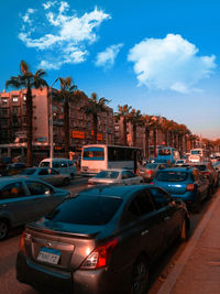 Cars on street by buildings against blue sky
