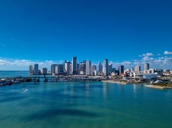 City at waterfront against blue sky