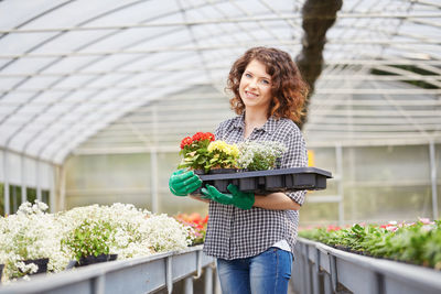 Portrait of woman with flowering plants in nursery