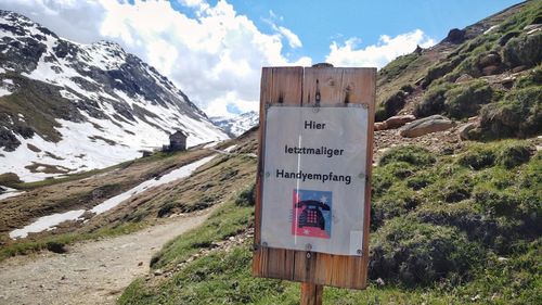 Information sign on road by mountain against sky