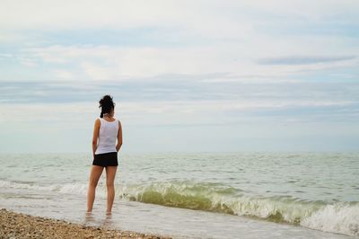 Rear view of woman standing at beach