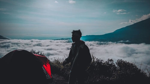 Rear view of people standing on mountain against sky
