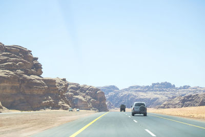 Road passing through mountains against clear sky