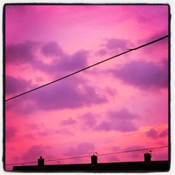 Low angle view of power lines against cloudy sky