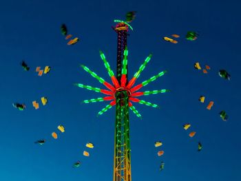 Low angle view of illuminated ferris wheel against clear blue sky