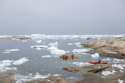 People on lake against sky during winter