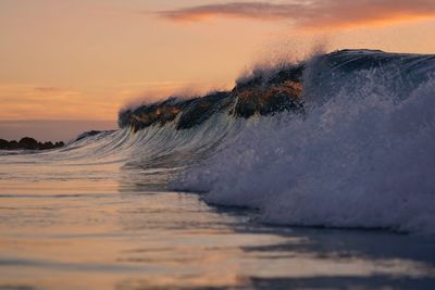 Sea waves splashing on shore during sunset