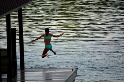 Rear view of girl jumping in sea