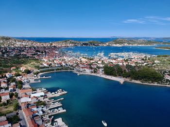 High angle view of townscape by sea against blue sky