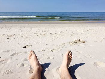 Low section of man relaxing on beach