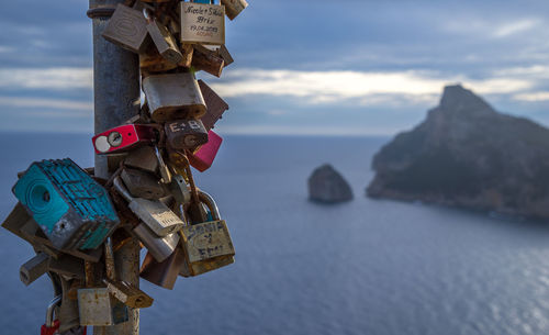 Close-up of old love locks on metal against sea during sunset