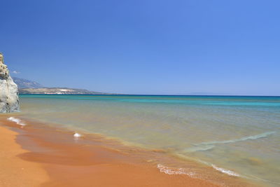 Scenic view of beach against clear blue sky