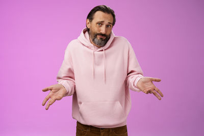 Portrait of man standing against pink background