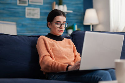 Portrait of young woman using laptop at home