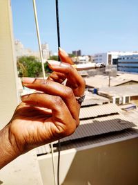 Close-up of person holding cigarette against sky