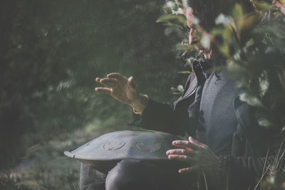 Man playing musical instrument while sitting in forest