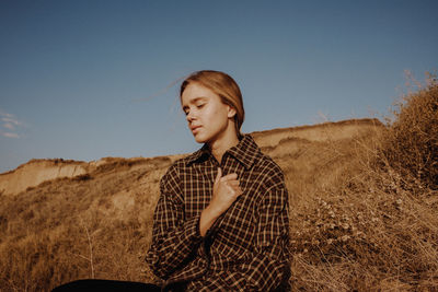 Full length of teenage girl standing on field against clear sky