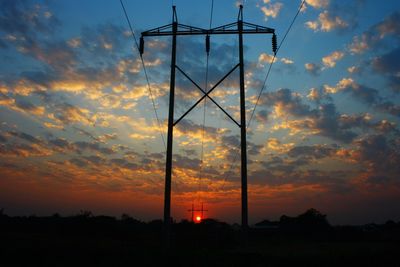 Electricity pylon against dramatic sky during sunset