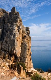 Rock formation on sea shore against sky