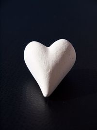 Close-up of heart shape on table against black background
