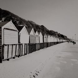 Beach huts by walkway against clear sky